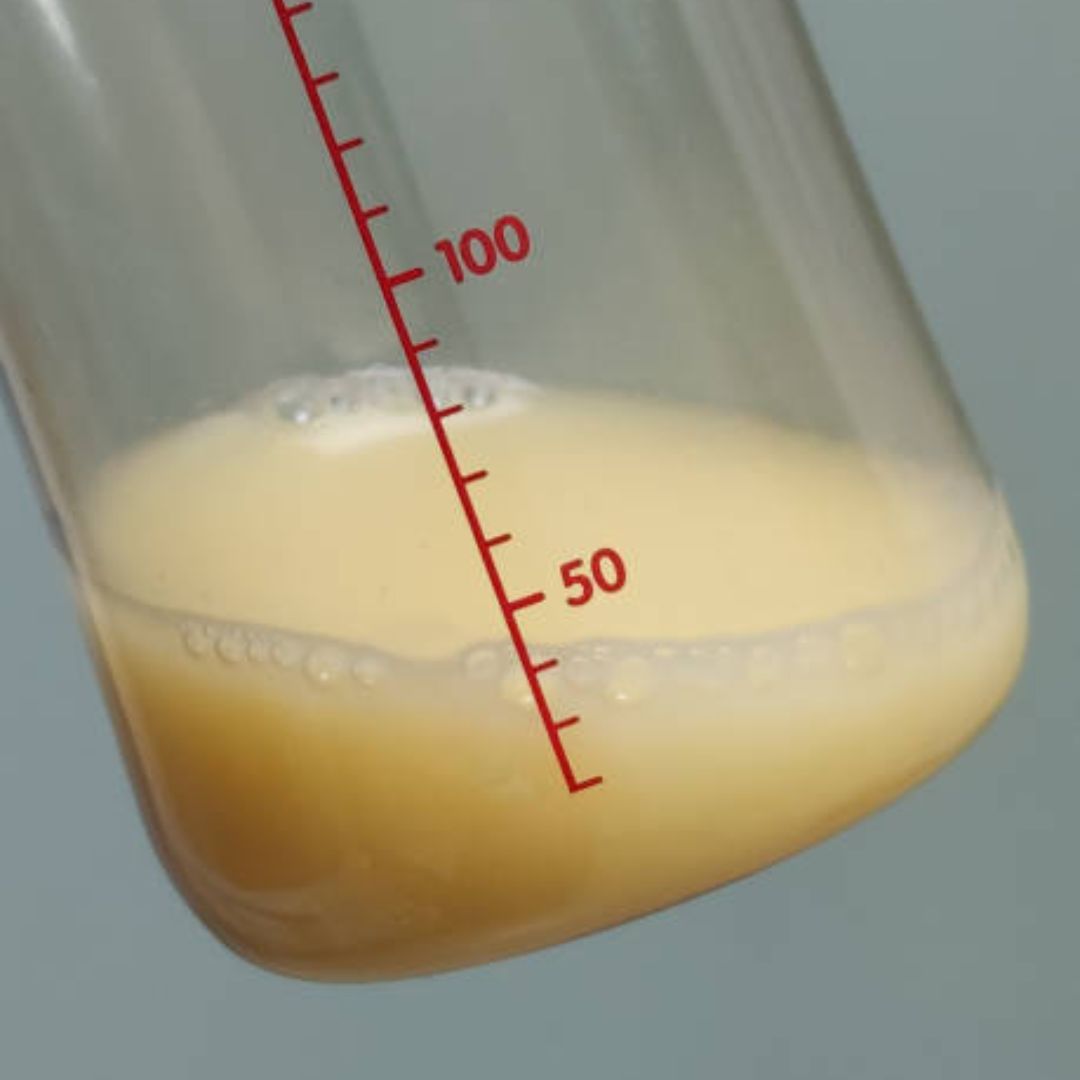 small clear bottle with less than 1 ounce or 30mL of yellow colored colostrum, tilted to the side